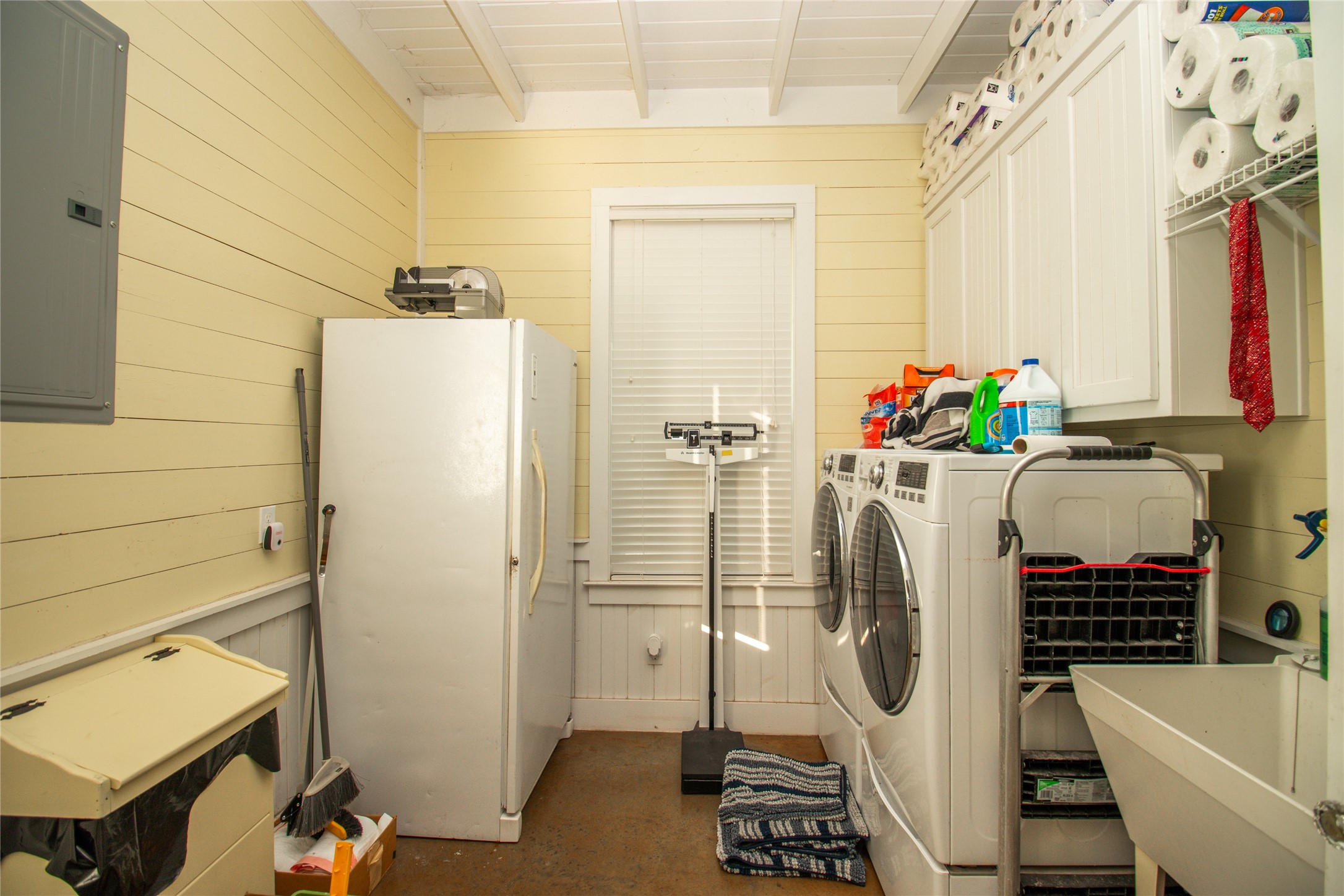 4237 County Road 330 Burnet, TX 78611 - Photo 24 of 40 Laundry area featuring wood walls, electric panel, finished concrete floors, beamed ceiling, and washing machine and dryer