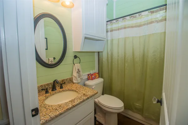 a bathroom with a granite countertop sink and a toilet