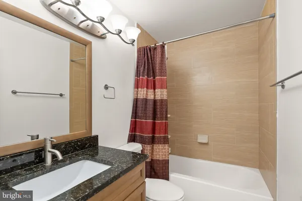 a bathroom with a granite countertop sink toilet and shower
