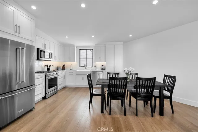 a kitchen with stainless steel appliances granite countertop a dining table chairs stove refrigerator and cabinets