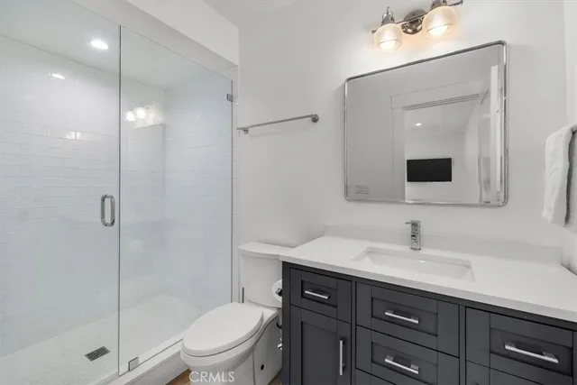 a bathroom with a toilet a sink a mirror a shower and vanity