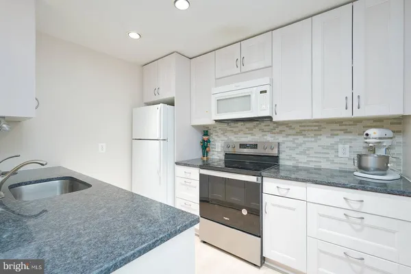 a kitchen with granite countertop a sink stove and refrigerator