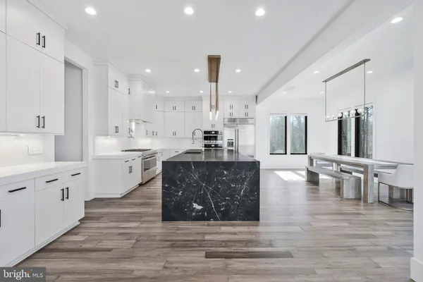 a large kitchen with granite countertop a stove a sink a dining table and chairs