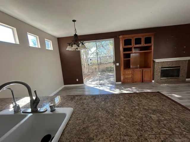 a view of a livingroom with a fireplace wooden floor and a kitchen space