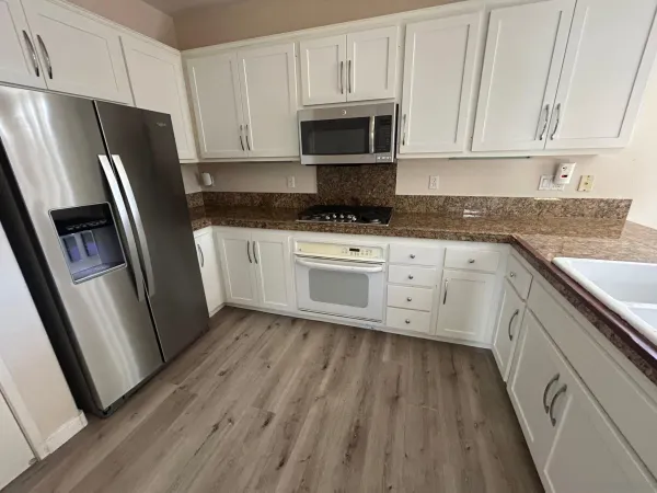 a kitchen with white cabinets stainless steel appliances a sink and a refrigerator