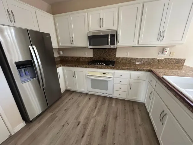 a kitchen with white cabinets stainless steel appliances a sink and a refrigerator