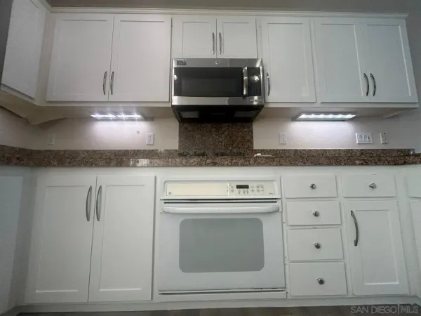 a kitchen with granite countertop white cabinets and stainless steel appliances