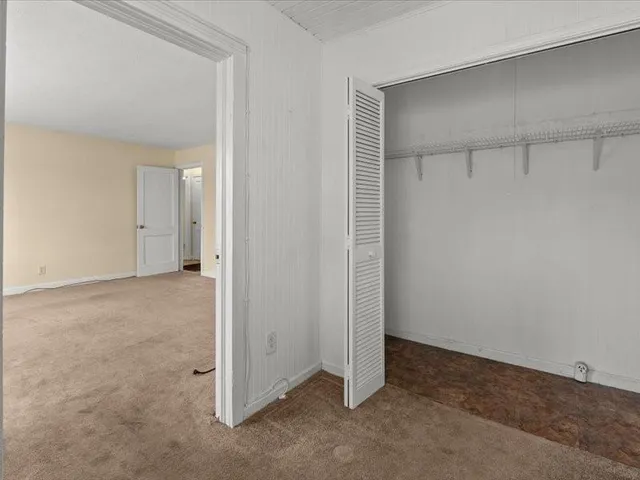 a view of an empty room with closet and a window