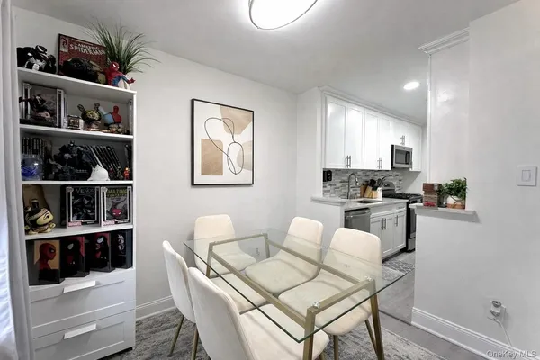 a kitchen with stainless steel appliances kitchen island granite countertop a refrigerator a stove and white cabinets with wooden floor