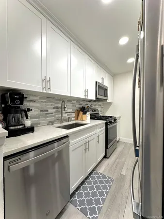 a kitchen with stainless steel appliances granite countertop a sink stove refrigerator and cabinets