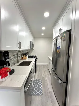a kitchen with stainless steel appliances granite countertop a refrigerator a sink a stove and white cabinets
