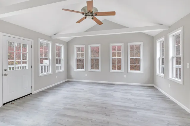 a view of an empty room with a window and wooden floor