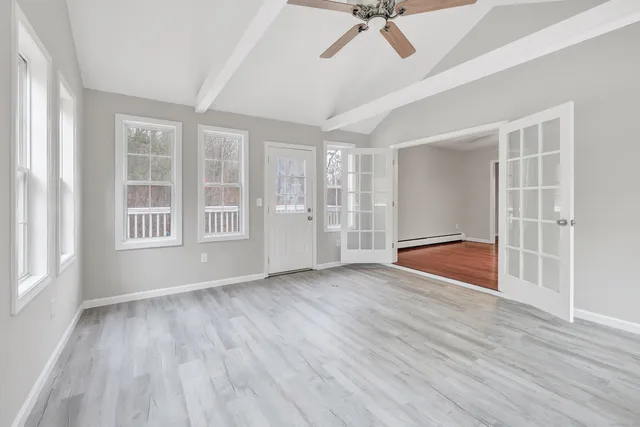 a view of an empty room with a window and wooden floor