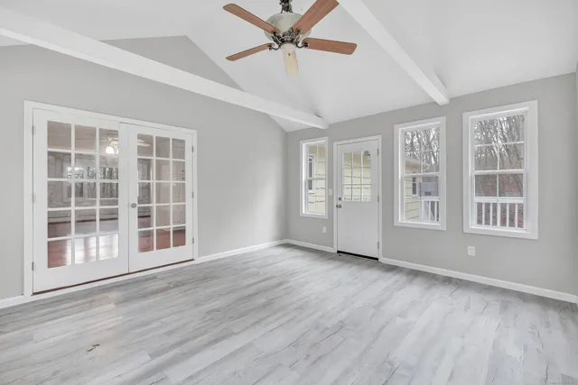 a view of an empty room with a window and wooden floor