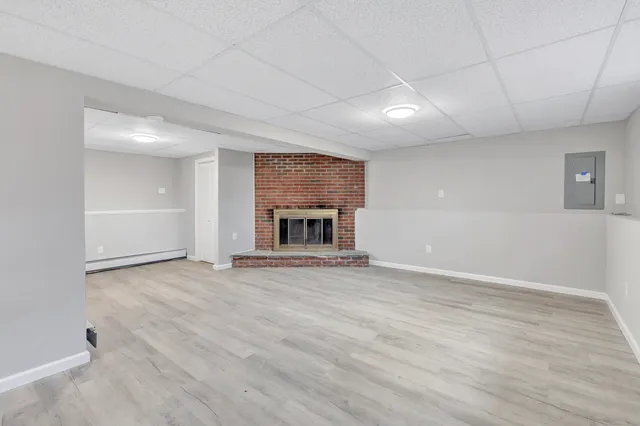 an empty room with wooden floor fireplace and windows