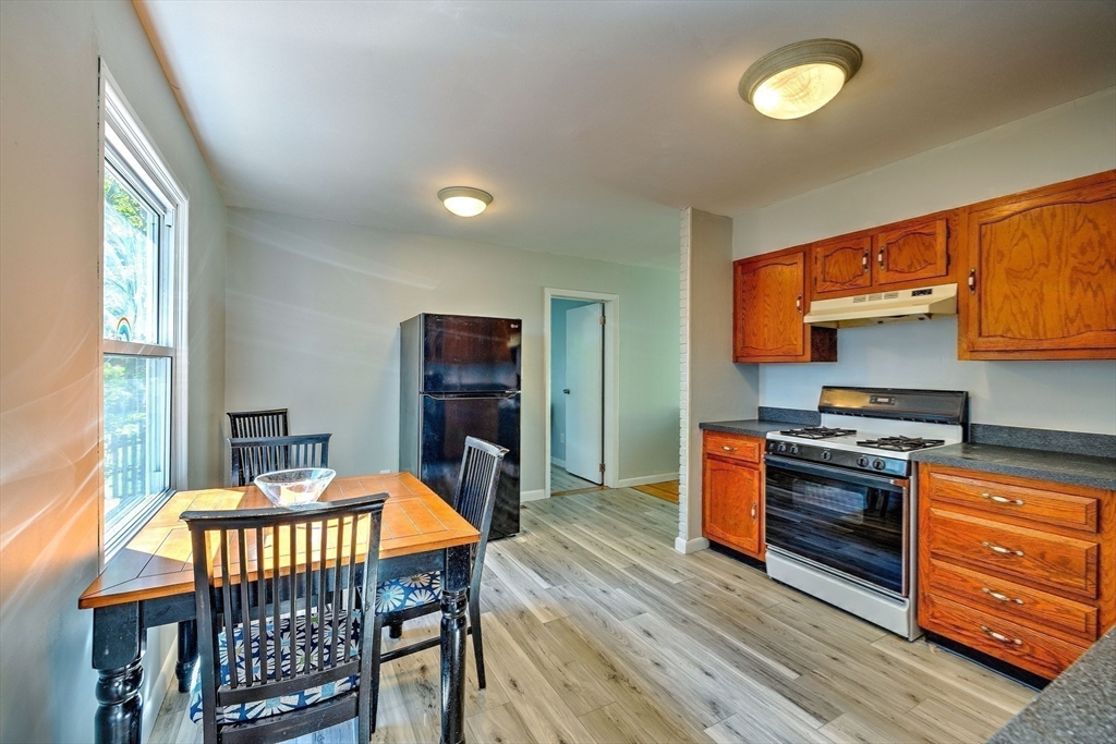 25 Tahanto Road Worcester, MA 01602 - Photo 20 of 35 a kitchen with stainless steel appliances granite countertop a stove top oven a sink dishwasher and a dining table with wooden floor