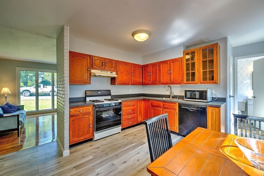 25 Tahanto Road Worcester, MA 01602 - Photo 21 of 35 a kitchen with stainless steel appliances granite countertop a stove top oven a sink dishwasher a dining table and chairs with wooden floor