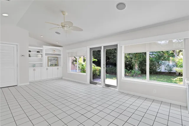 an empty room with wooden floor cabinet and windows