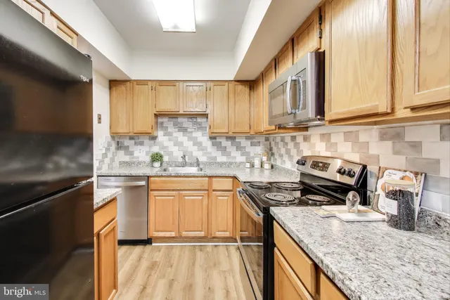 a kitchen with stainless steel appliances granite countertop a stove a sink and a white cabinets