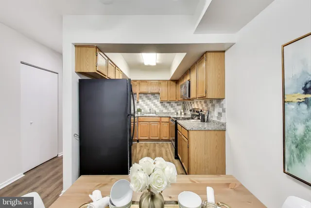 a kitchen with stainless steel appliances kitchen island granite countertop a refrigerator and a wooden floor