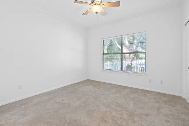 an empty room with a window and a ceiling fan