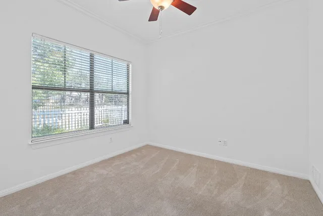 an empty room with chandelier fan and windows