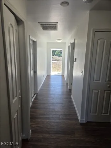 an empty room with wooden floor cabinet and windows