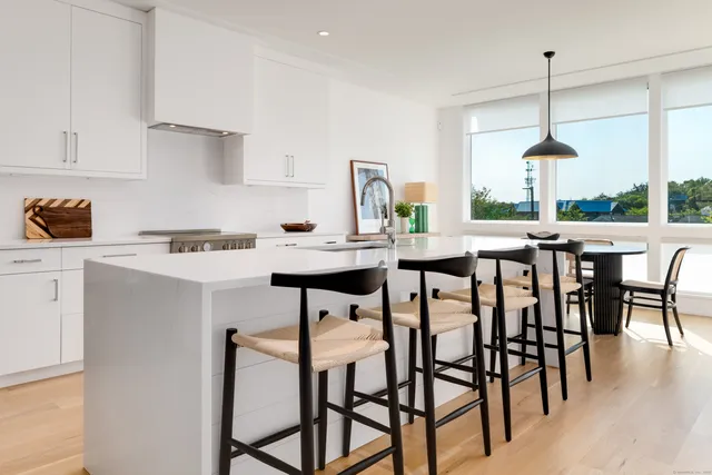 a kitchen with stainless steel appliances a dining table chairs and white cabinets next to a window