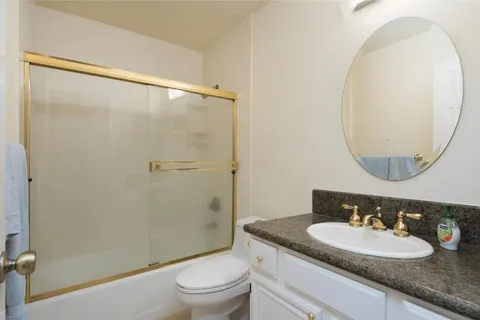 a bathroom with a granite countertop sink toilet and a mirror