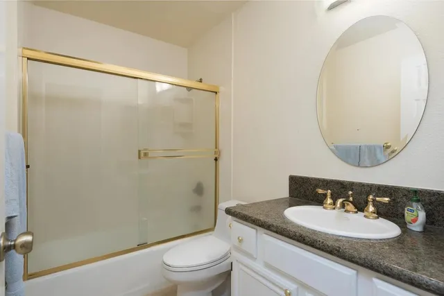 a bathroom with a granite countertop sink toilet and a mirror