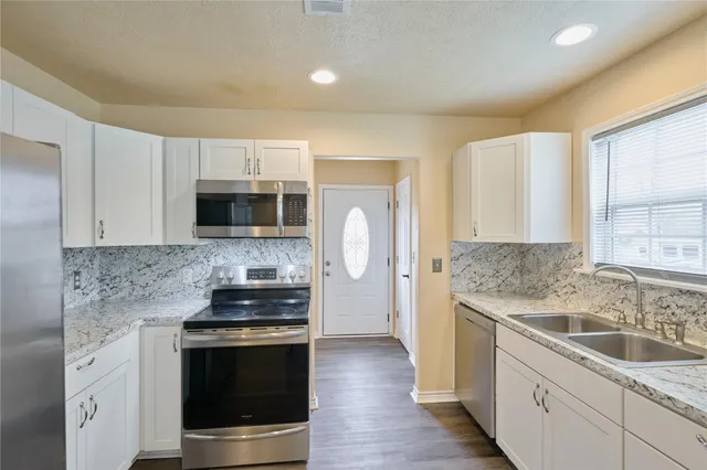 a kitchen with stainless steel appliances granite countertop a sink stove and microwave
