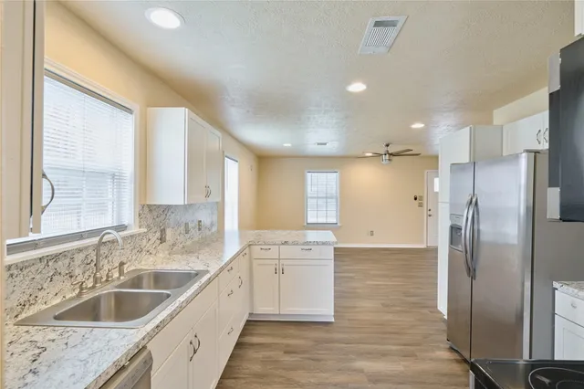 a large kitchen with stainless steel appliances granite countertop a sink and a refrigerator