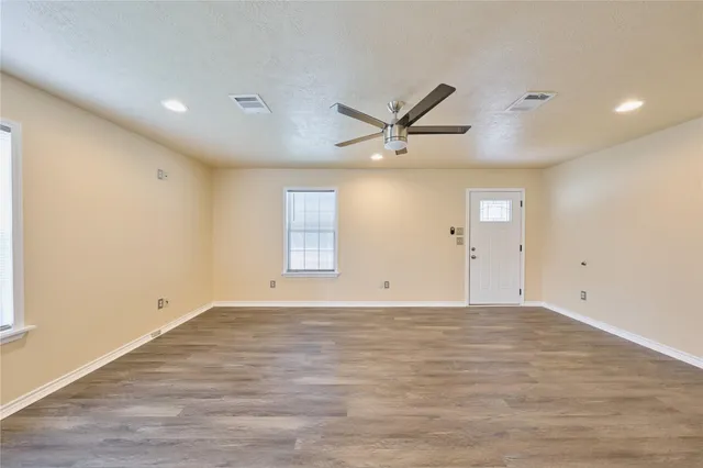 an empty room with wooden floor and windows