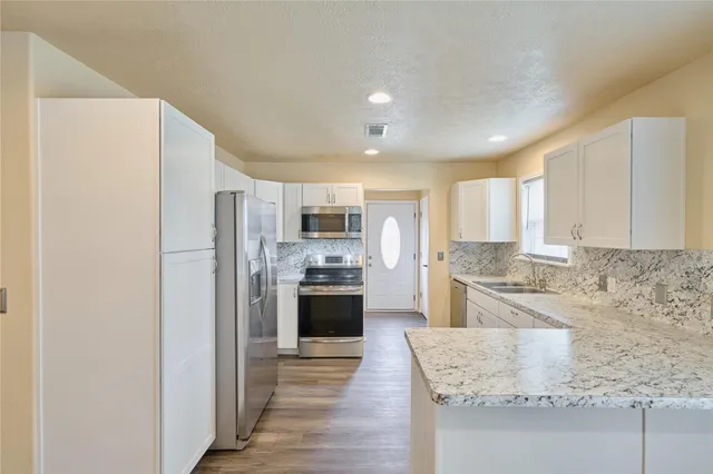 a kitchen with stainless steel appliances granite countertop a refrigerator sink and stove