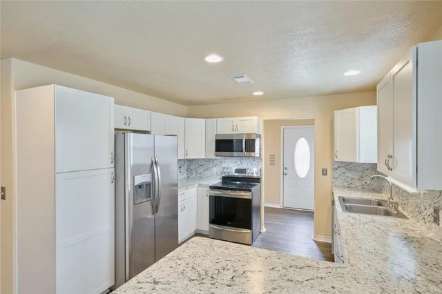 a kitchen with stainless steel appliances kitchen island granite countertop a refrigerator and a stove top oven
