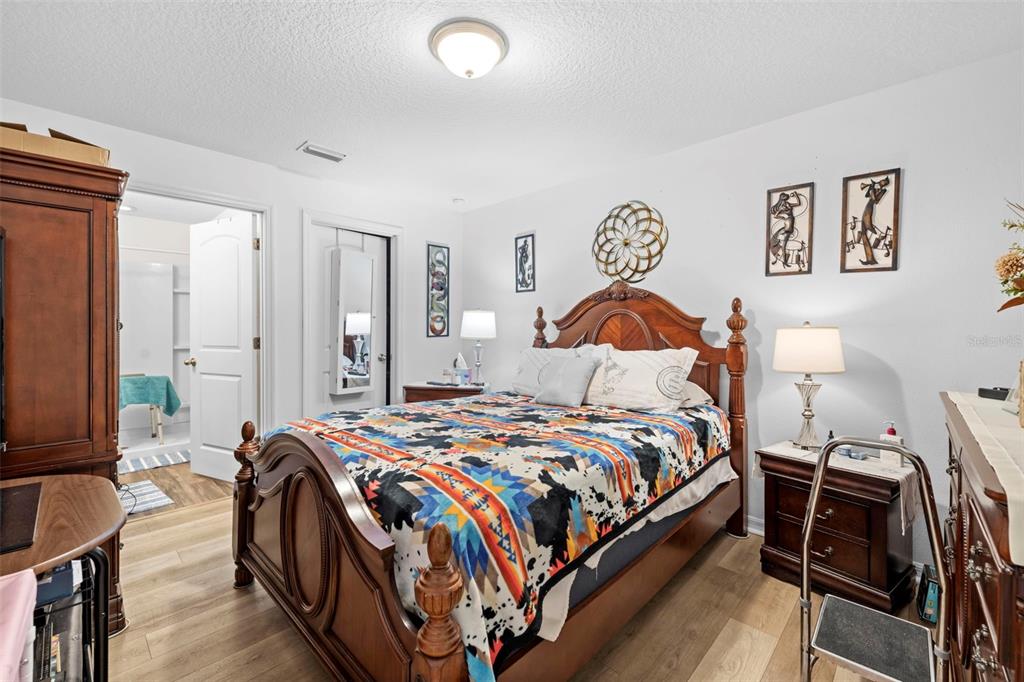 26448 Bertram Road Brooksville, FL 34602 - Photo 23 of 31 a bedroom with a bed and dresser with wooden floor