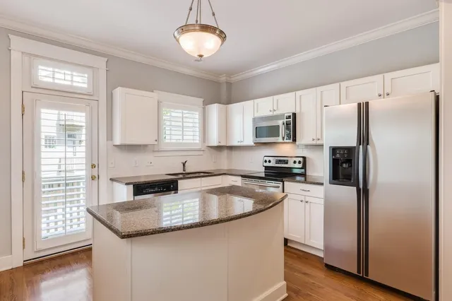 a kitchen with granite countertop stainless steel appliances a refrigerator a stove a sink a center island and cabinets