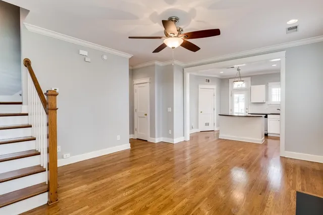 a view of an empty room with wooden floor and a ceiling fan