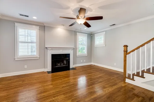 a view of an empty room with wooden floor fireplace and a window