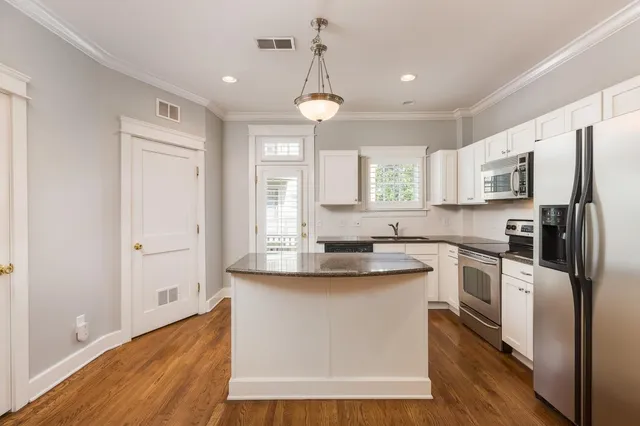 a kitchen with a refrigerator a sink dishwasher a stove and white cabinets with wooden floor