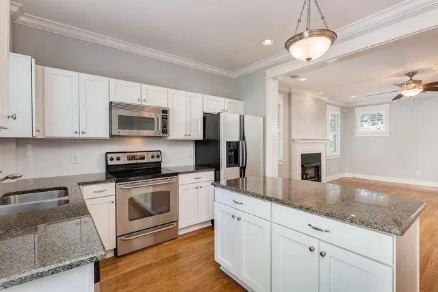 a kitchen with stainless steel appliances granite countertop a sink a stove top oven a refrigerator cabinets and wooden floor