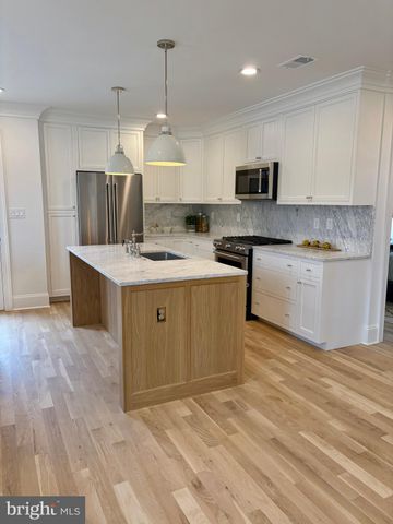 a kitchen with stainless steel appliances granite countertop a sink a stove a refrigerator and island with wooden floor