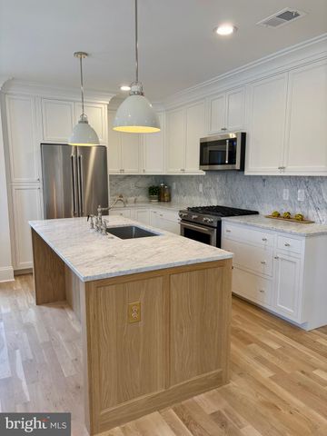 a kitchen with stainless steel appliances granite countertop a sink a stove a refrigerator and island with wooden floor