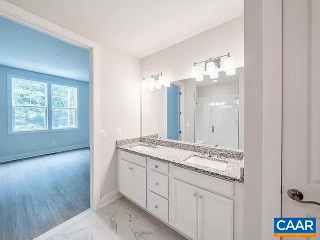 a spacious bathroom with a granite countertop sink a mirror and a shower