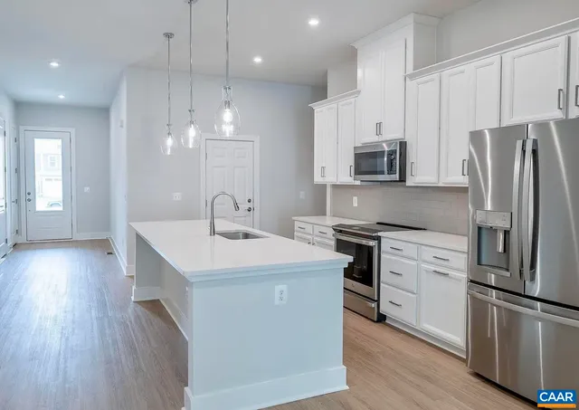 a kitchen with stainless steel appliances white cabinets a sink and a refrigerator