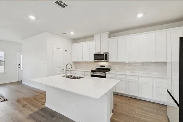 a kitchen with sink a microwave and cabinets