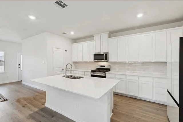 a kitchen with sink a microwave and cabinets