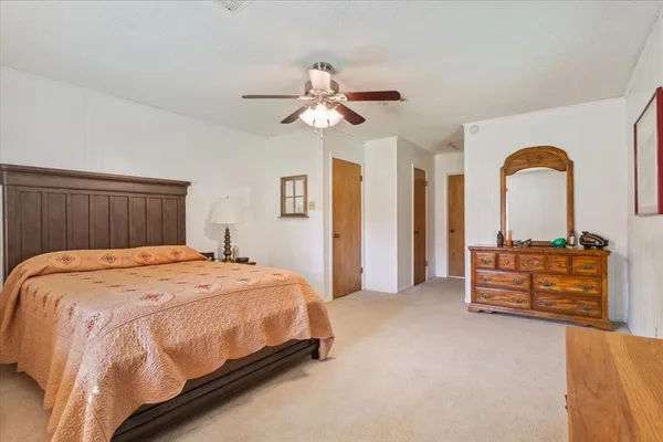 a spacious bedroom with a bed a dresser and a chandelier