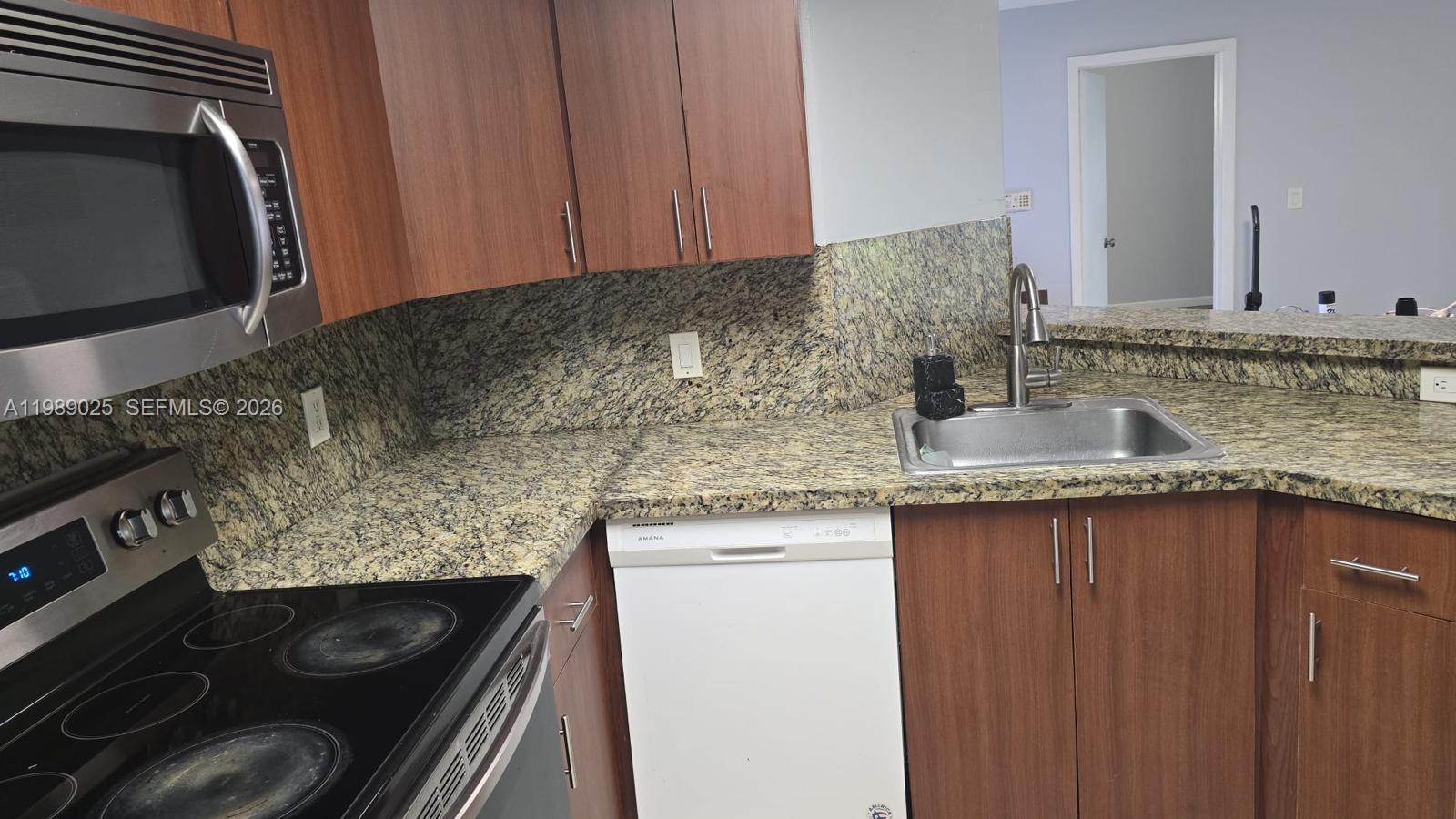 8821 Wiles Road, Unit 108 Coral Springs, FL 33067 - Photo 11 of 46 a kitchen with granite countertop a sink stove and cabinets