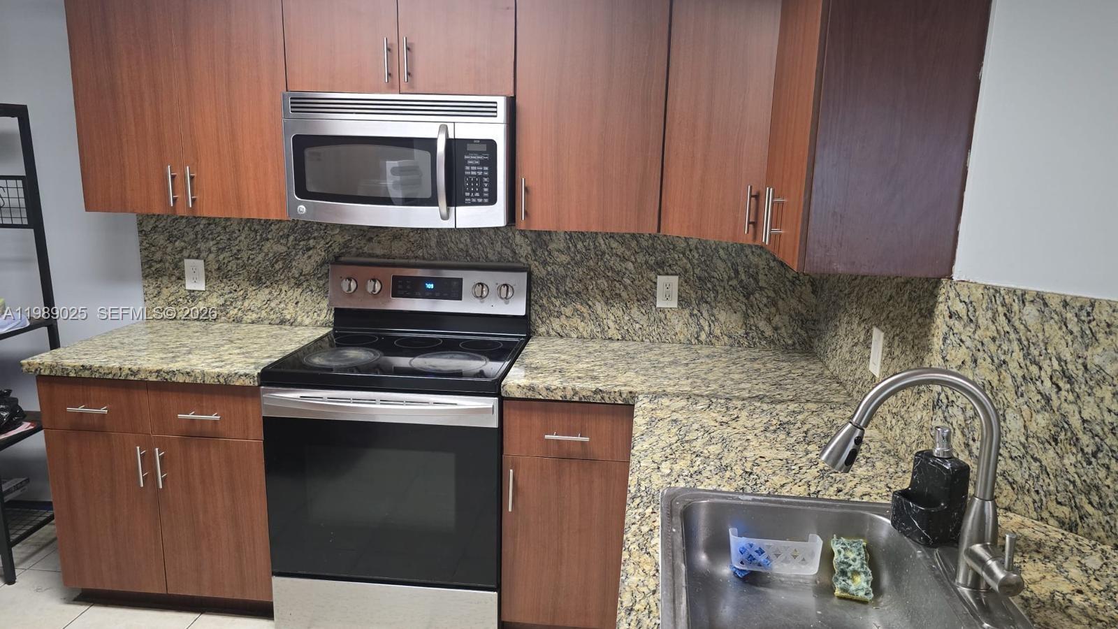 8821 Wiles Road, Unit 108 Coral Springs, FL 33067 - Photo 12 of 46 a kitchen with granite countertop a stove top oven microwave and cabinets